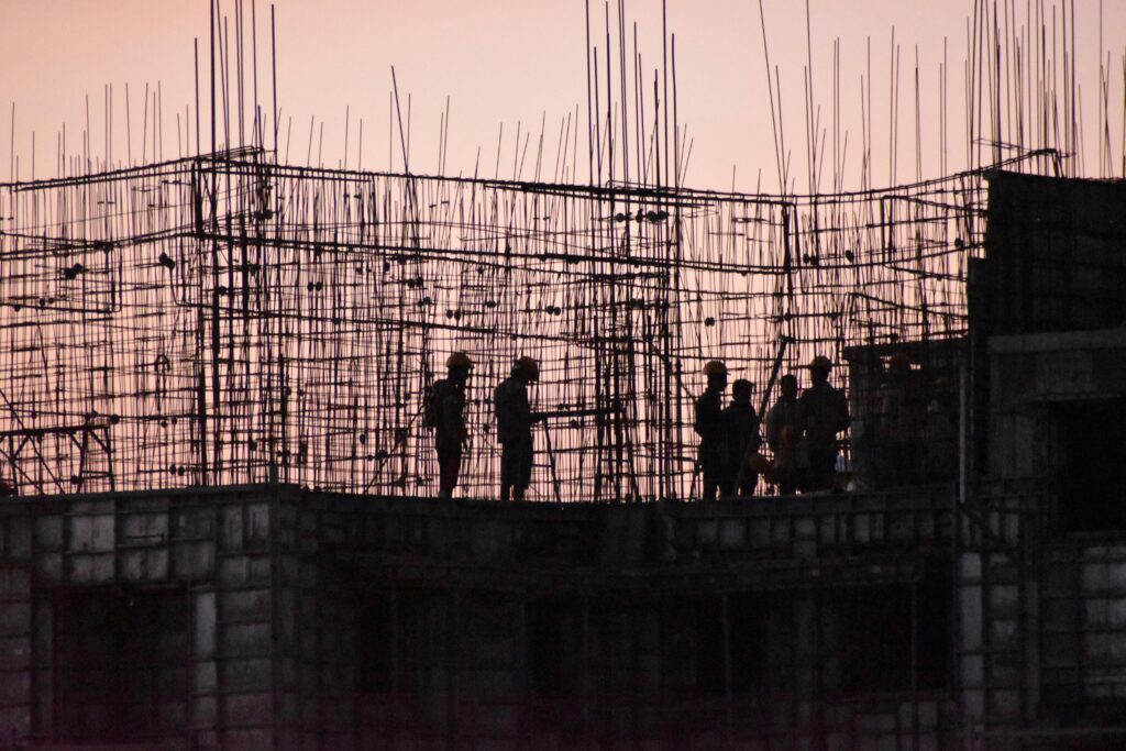 Silhouettes of workers at a construction site in India during sunset.
